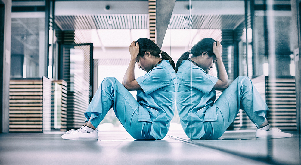 distraught nurse leaning against reflective wall