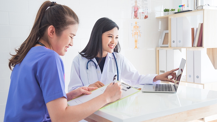 medical providers smile while looking at computer