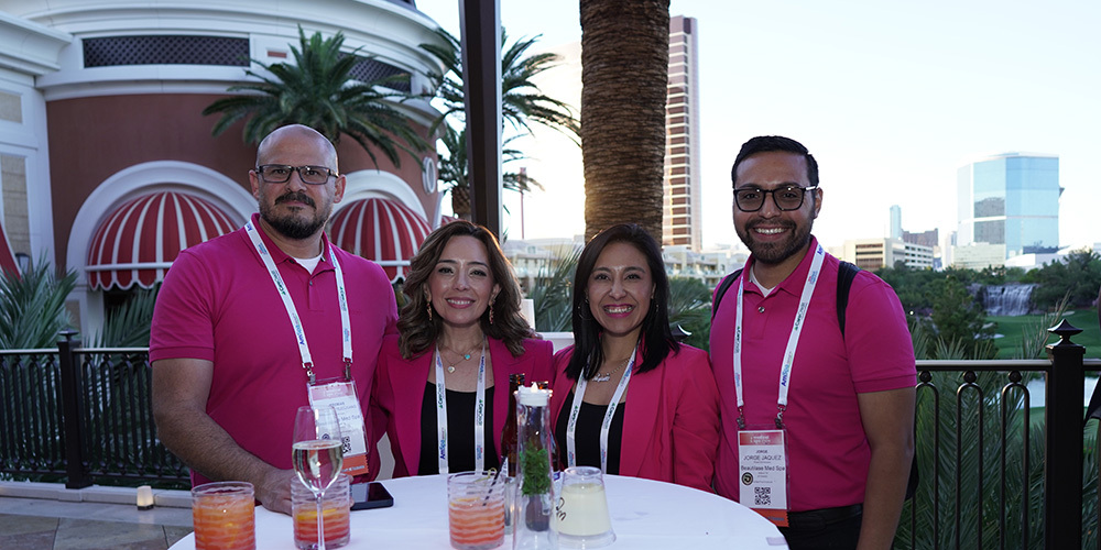 Four AmSpa members dressed in pink enjoy cocktails during the sunset sips at Medical Spa Show 2024.