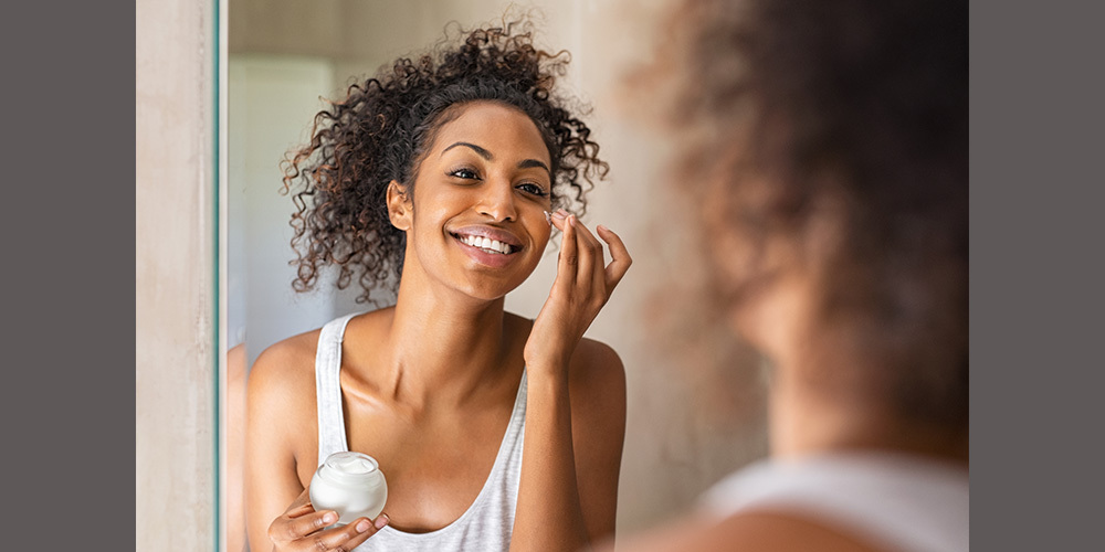 Woman of color applies skin care