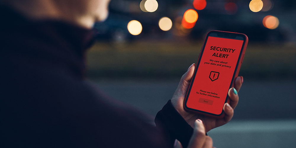 man looks at phone displaying security alert message