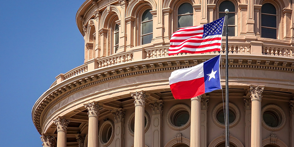 american and texas flags in front of state capitol