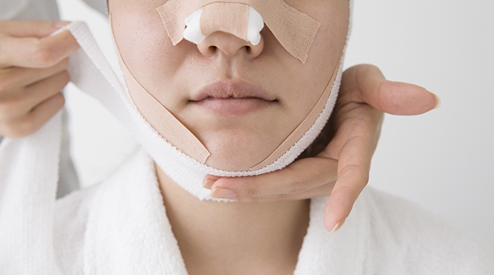 Young woman's face is bandaged after treatment
